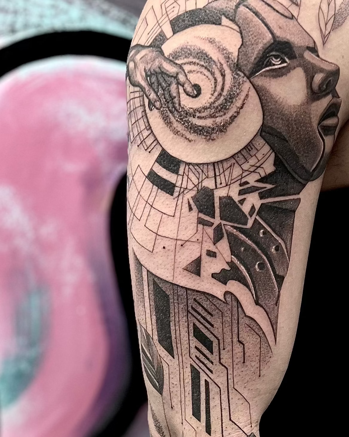 Person with a heavily tattooed arm in front of a colorful abstract background