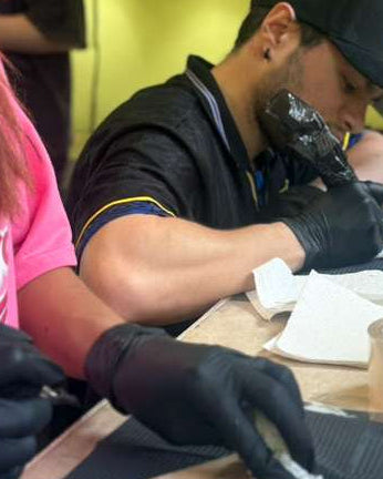 Person getting a tattoo in a tattoo parlor with a bright yellow wall.